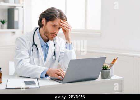 Besorgt männlichen Arzt Blick auf schlechte Testergebnisse auf Laptop Stockfoto
