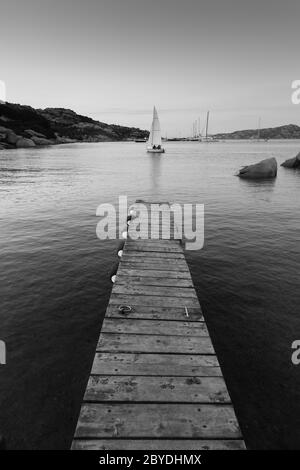 Holzsteg und Segelboote segeln am Abend ruhiges Meer von herrlichen Porto Rafael, Costa Smeralda, Sardinien, Italien. Symbol für Entspannung, Reichtum Stockfoto