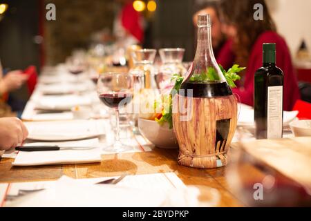 Catering-Services Hintergrund. Tisch mit Rotweinflasche und Gläsern mit Snacks und unerkennbaren Menschen essen in einem Restaurant. Abendessen im Hotel. Auswahl Stockfoto