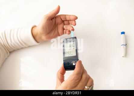 Nahaufnahme der Hände einer Frau Testen ihres hohen Blutzuckerspiegels mit Glucometer, Blutzuckermessgerät. Der Blutzuckerwert ist noch unbekannt und wird gemessen Stockfoto