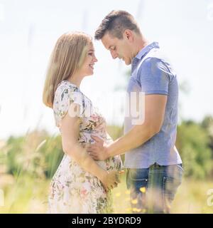 Junge glücklich schwanger Paar umarmen in der Natur. Stockfoto