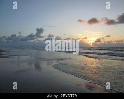 Die Morgendämmerung bricht über dem Wasser und den Wellen des Packery Channel Jetty Beach, Padre Island, Texas, Konzept für Urlaub, Tourismus, Strände, Lifestyle Stockfoto