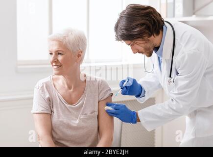 Arzt, der eine Impfung für ältere Patientinnen macht Stockfoto