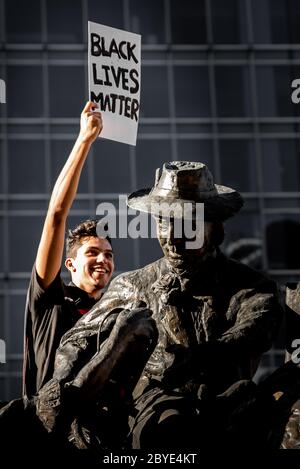 Junger Mann auf Statue am BLM Protest, King George Square Stockfoto