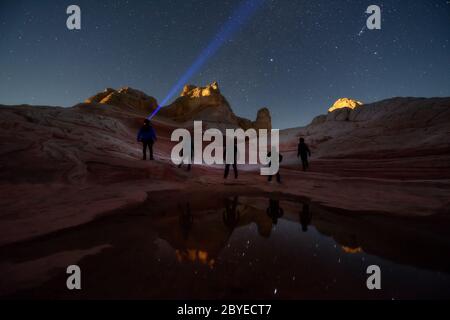 Eine Gruppe von Sternguckern, die unter dem Nachthimmel voller Sterne in White Pocket, einem abgelegenen Gebiet in der Wüste von Arizona, postet. Reise- und Abenteuerthema im Frühling. Stockfoto