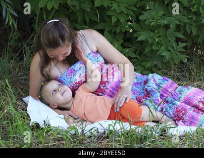 Schöne schwangere Frau beschäftigt sich zärtlich mit einer kleinen Tochter. Stockfoto