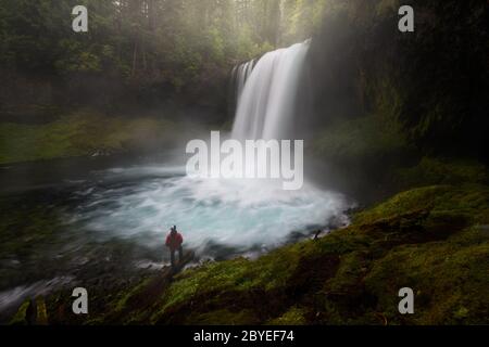 Koosah Falls mit glazialen maeltblauen Wasser. Ein Mann, der für den Sinn für Maßstab in der Szene steht. Stockfoto