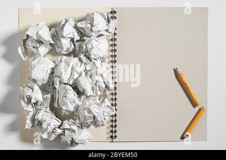 Notizblock, gebrochener Bleistift und zerknitterte Papierkugeln auf weißem Hintergrund. Konzeptfoto Stockfoto