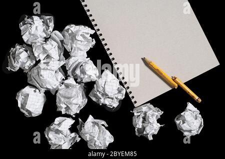 Notizblock, gebrochener Bleistift und zerknitterte Papierkugeln auf schwarzem Hintergrund. Konzeptfoto Stockfoto