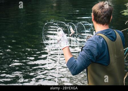 Junger Mann, der eine Krabbenfalle auswirft, Krabbenfischen, Sommer in Schweden Stockfoto