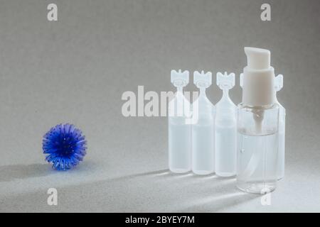 Abstraktes Modell des Coronavirus, Ampulle mit Medizin und Flasche mit antibakteriellem Gel für Hände auf grauem Hintergrund. Hygienekonzept zur Bekämpfung des Virus. Stockfoto