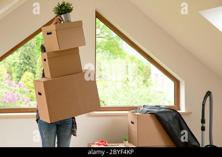 Verschieben. Pappkartons für den Umzug in ein neues, sauberes Zuhause. An einem sonnigen Tag durch ein Fenster im Dachgeschoss. Stockfoto