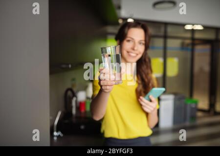 Schöne schlanke Mädchen hält ein Glas Wasser nach vorne. Stockfoto