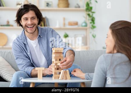 Lustiger Kerl spielt Jenga mit Freundin zu Hause Stockfoto