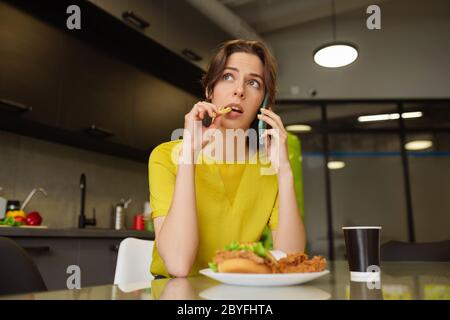 Frau spricht auf dem Smartphone essen pommes Frites. Stockfoto