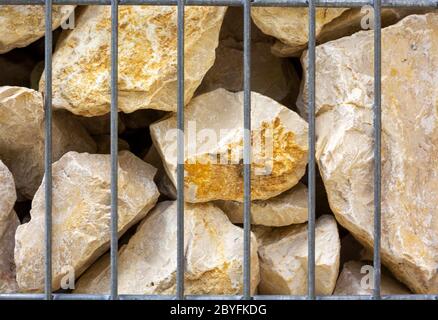 Gelbe Kalksandsteine in einem Stahlgabion Stockfoto