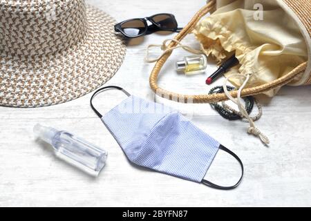 Stoff handgemachte Maske und Desinfektionsmittel Hand auf einem Tisch mit Handbad und Beauty-Accessoires und Sommer Hut Stockfoto