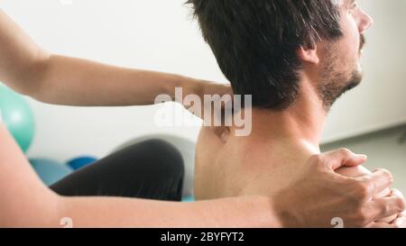 Physiotherapeut, der Massage und Dehnung mit Person auf einem Behandlungstisch macht. Stockfoto