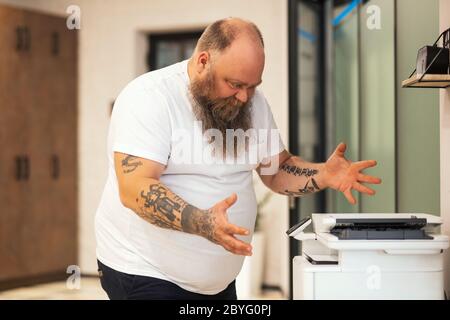 Kahl bärtig plus Größe Mann, der Kopie auf xerox und Gefühl verärgert Stockfoto