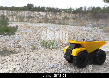 Gelber Bergwerkswagen mit Steinen auf hohen Bergen in der Nähe von Steinbruch. Stockfoto