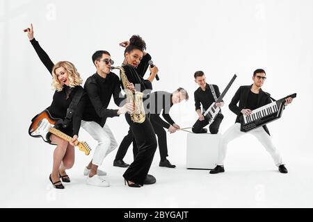 Unterhaltsames Konzept, Teamwork. Internationale Gruppe von Musikern auf weißem Hintergrund, Gitarrist, Schlagzeuger, Solisten, Saxophonist. Stockfoto