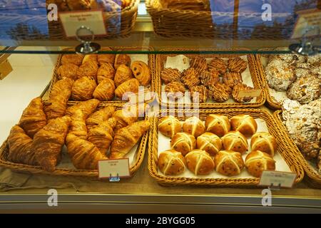 Körbe mit Butter Mandelschokolade Croissant, Hot Cross Brötchen, Schinken und Käse Tiger Claw, Bacon und Schinken Sandwiches, Kouign Amann und Ahorn auseinander ziehen Stockfoto