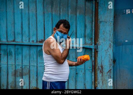 San Pedro Sula, Honduras. Mai 2020. Ein Mann, der eine Gesichtsmaske als vorbeugende Maßnahme trägt, isst während der Sperrung eine Pfote.Honduras hat eine "intelligente Wiedereröffnung" ins Auge gedrungen, die es allen kommerziellen Geschäften erlaubte, sich zu öffnen, aber alle Mitarbeiter und Kunden dazu aufforderte, Masken zu tragen. Kredit: Seth Sidney Berry / SOPA Images / ZUMA Wire / Alamy Live News Stockfoto