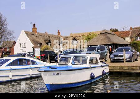 Ein Blick vom Fluss des Staithe n Willow Cafe in Horning auf den Norfolk Broads. Mit festangefahrenden Cruisers und Autos auf dem Parkplatz Stockfoto