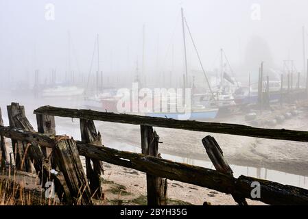 Boote liegen am Oare Creek, nahe Faversham in Kent. Ebbe und Nebel am frühen Morgen. Stockfoto