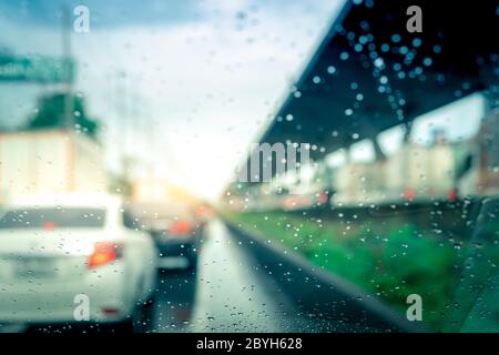 Regentropfen auf Windschutzscheibe. Auto fahren auf Asphaltstraße an regnerischen Tag. Windschutzscheibe des Autos mit Regentropfen auf Glas Windschutzscheibe. Stau bei Regen Stockfoto