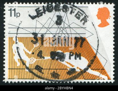 GROSSBRITANNIEN - UM 1977: Briefmarke gedruckt von Großbritannien, zeigt zwei Sportler spielen Tennis, um 1977. Stockfoto