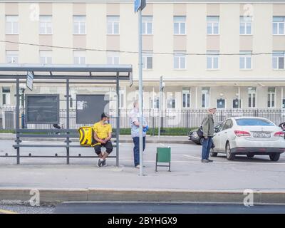 Moskau, Russland. Juni 09, 2020. Passagiere in medizinischen Masken und Schutzhandschuhen an einer Haltestelle des öffentlichen Verkehrs warten auf die Ankunft des Busses. Stockfoto