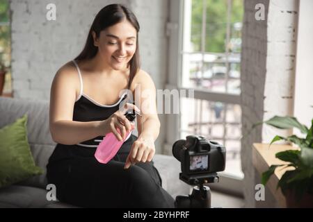 Feuchtigkeitscreme. Kaukasische Bloggerin Frau machen vlog, wie man Körper positiv und unter Schönheitsbehandlung. Lifestyle, Influencer Frauen, gesundes Konzept. Mit der Kamera, Aufnahme ihrer Kosmetik-Test, Tutorials. Stockfoto