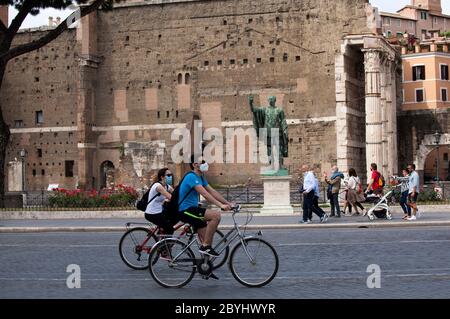 Italien Wiedereröffnung, Start Phase 3. Personen, die eine Schutzmaske tragen, gehen am Dienstag, den 02. Juni 2020 in Rom in der Straße Fori Imperiali nahe dem Kolosseum (Colosseo) umher. Stockfoto