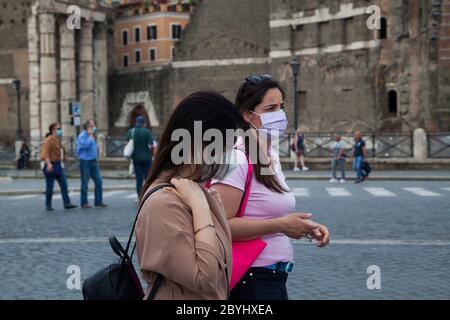 Italien Wiedereröffnung, Start Phase 3. Personen, die eine Schutzmaske tragen, gehen am Dienstag, den 02. Juni 2020 in Rom in der Straße Fori Imperiali nahe dem Kolosseum (Colosseo) umher. Stockfoto