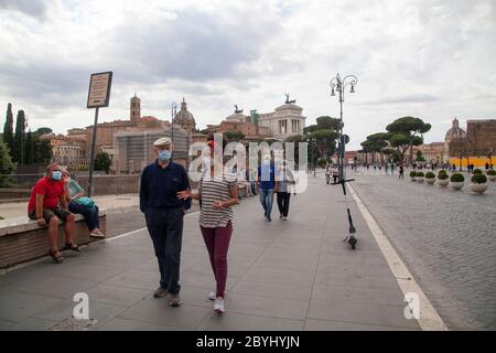 Italien Wiedereröffnung, Start Phase 3. Personen, die eine Schutzmaske tragen, gehen am Dienstag, den 02. Juni 2020 in Rom in der Straße Fori Imperiali nahe dem Kolosseum (Colosseo) umher. Stockfoto