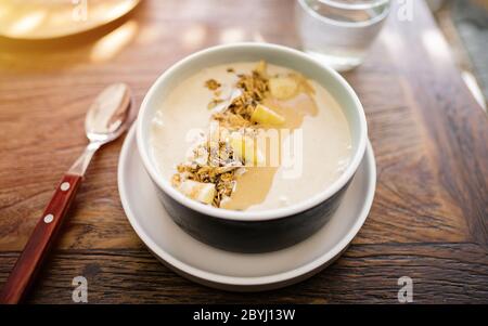 Essen Frühstücksschale. Joghurt, Erdbeere, Heidelbeere, Samen, Kokosnuss, frische und trockene Früchte in weiß Keramik Schüssel in den Händen. Sauberes Essen, Diät Stockfoto