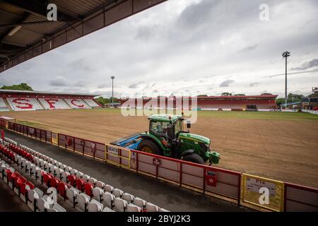 Traktor auf Fußball / Fußballplatz auf Sportplatz während der Saisonende Arbeit von Bodenpersonal Umlagerung Rasen. Stockfoto