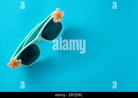 Sonnenbrille mit Blumen auf blauem Hintergrund Stockfoto