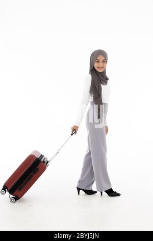 Voller Körper Portrait von glücklichen asiatischen muslimischen Touristen Frau mit Hijab halten roten Koffer Gepäck erhalten für Reisen und Reise bereit. Studio shot Stockfoto