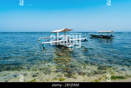 Fischerboot. Landschaft bei Sonnenaufgang. Traditionelle balinesische Bootsanlegestelle. Fischerboot am Strand. Wasserspiegelung. Sanur Beach, Bali, Indonesien. Stockfoto