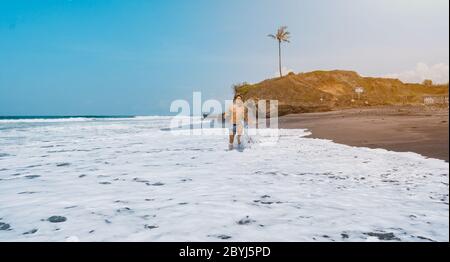Sportlicher Fitness-Mann Läufer läuft am Sonnenaufgangstrand. Leerer Strand in Bali, Indonesien. Sportlich attraktive Leute joggen am Strand und genießen die Sonne Stockfoto