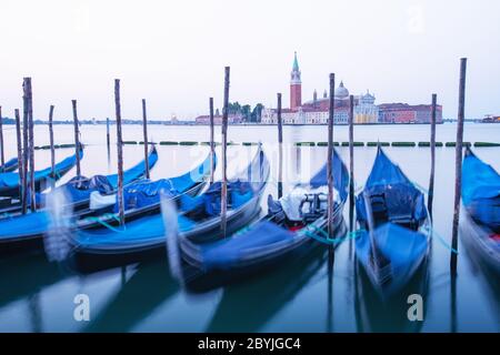 Ruhige Landschaft mit klarem Himmel über dem markusplatz in Venedig. Reihe von Gondeln auf dem Pier der Stadt geparkt. Kirche von San Giorgio Maggiore auf Hintergrund, Italien, Europa Stockfoto