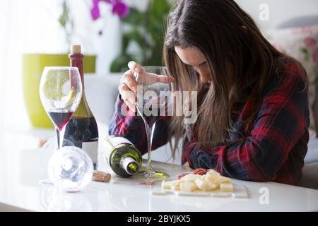 Traurige müde Frau, Wein zu Hause trinken, allein, auf dem Boden im Wohnzimmer sitzen, Gefühl depressiv Stockfoto