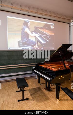 Freiburg Im Breisgau, Deutschland. Juni 2020. Momoko Watabe ist via Skype verbunden und spielt in einem Prüfungsraum der Musikhochschule Freiburg über eine zweite Internetverbindung in Tokio Klavier. Da koronabedingte Reisebeschränkungen derzeit internationale Bewerber erschweren, dürfen Klavieranwärter der Musikhochschule Freiburg erstmals über ein ferngesteuertes Klavier Klavier spielen. Quelle: Philipp von Ditfurth/dpa/Alamy Live News Stockfoto