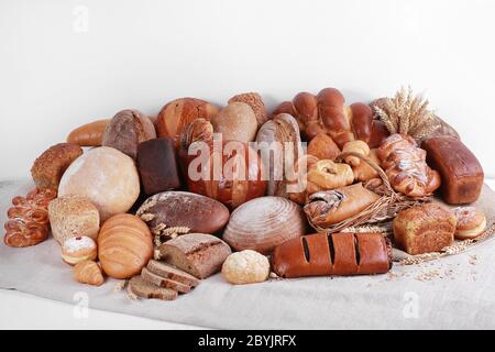 Verschiedene Arten von Backwaren auf Leinen und weißen Wandhintergrund. Stockfoto