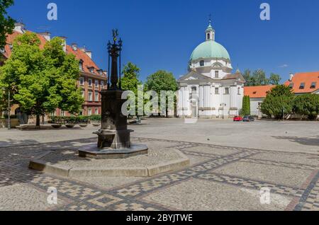 Warschau, Masowien Provinz, Polen. Newtown Marktplatz mit barocker Saint Casimir Kirche und historischem Brunnen in der Mitte. Stockfoto