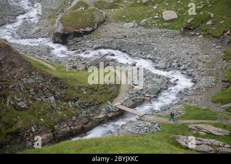 Tourist über die kleine Brücke in den österreichischen Alpen. Wanderreise Outdoor-Konzept, Reise in die Berge, Kals am Großglockner, Aust Stockfoto