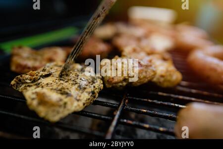 Gegrilltes Fleisch im Grill mit Flammen und Kohlen am Nachmittag des Wochenendes. Nahaufnahme frisch gegrilltes Fleisch auf dem Grill. Stockfoto