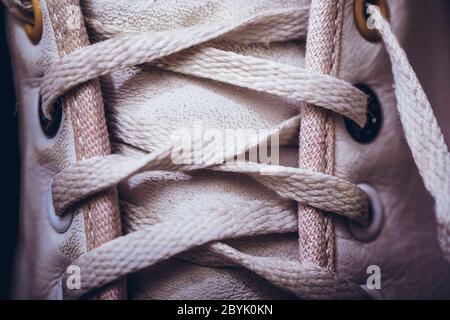 Nahaufnahme Schnürung Hintergrundstruktur für Design. Bild von oben von weißen Sneakers. Schnürung auf weißen Lederschuhen aus nächster Nähe. Stockfoto